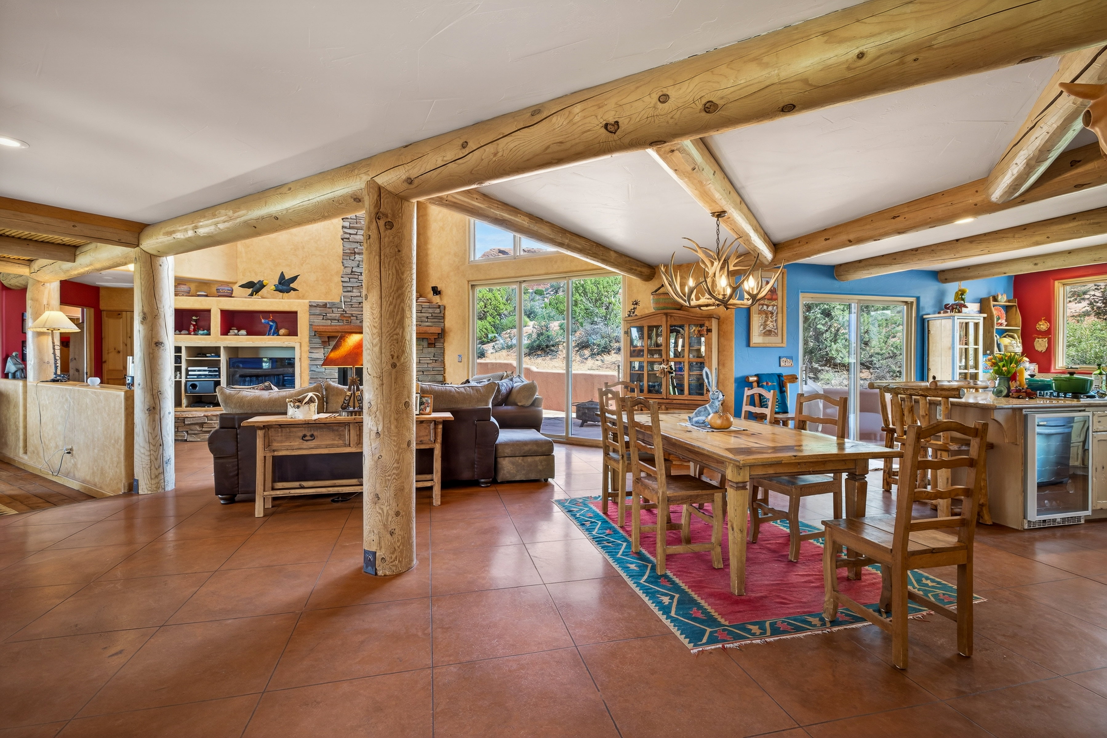 Dining room featuring wine cooler, a chandelier, healthy amount of natural light, tile patterned floors, and lofted ceiling with beams