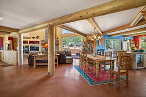Dining room featuring wine cooler, a chandelier, healthy amount of natural light, tile patterned floors, and lofted ceiling with beams