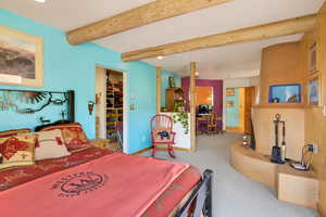 Bedroom with beamed ceiling, light colored carpet, recessed lighting, and a spacious closet