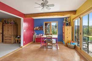Dining area featuring ceiling fan, beamed ceiling, and light tile patterned floors