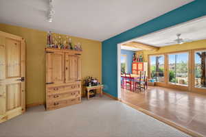 Living area featuring light carpet, ceiling fan, rail lighting, and light tile patterned flooring