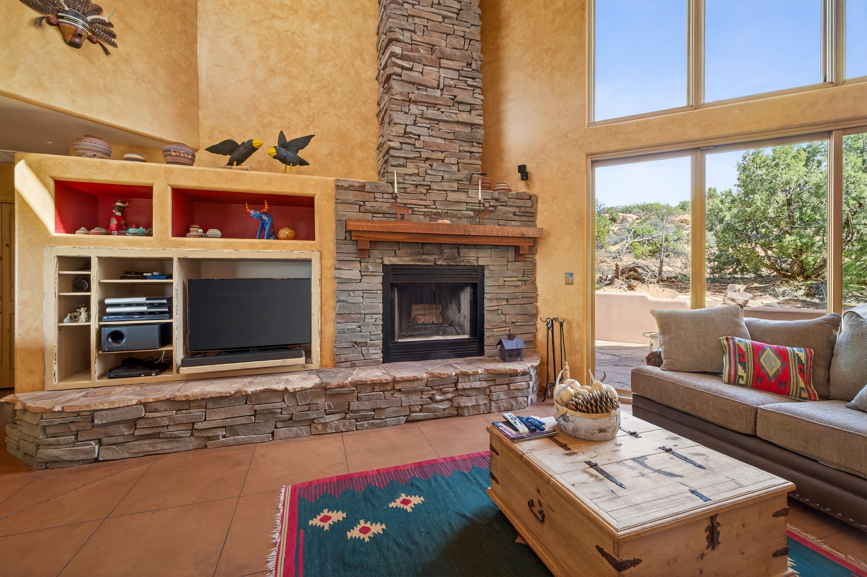 Living room with a high ceiling, a stone fireplace, and tile patterned flooring