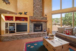 Living room with a high ceiling, a stone fireplace, and tile patterned flooring