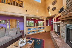 Living room featuring a high ceiling, a fireplace, and dark tile patterned flooring