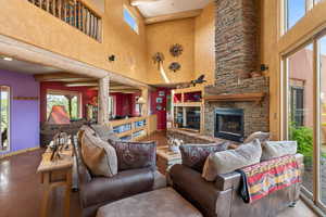 Living area featuring healthy amount of natural light, a high ceiling, and a stone fireplace