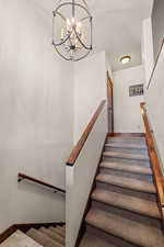Stairs featuring a chandelier and baseboards