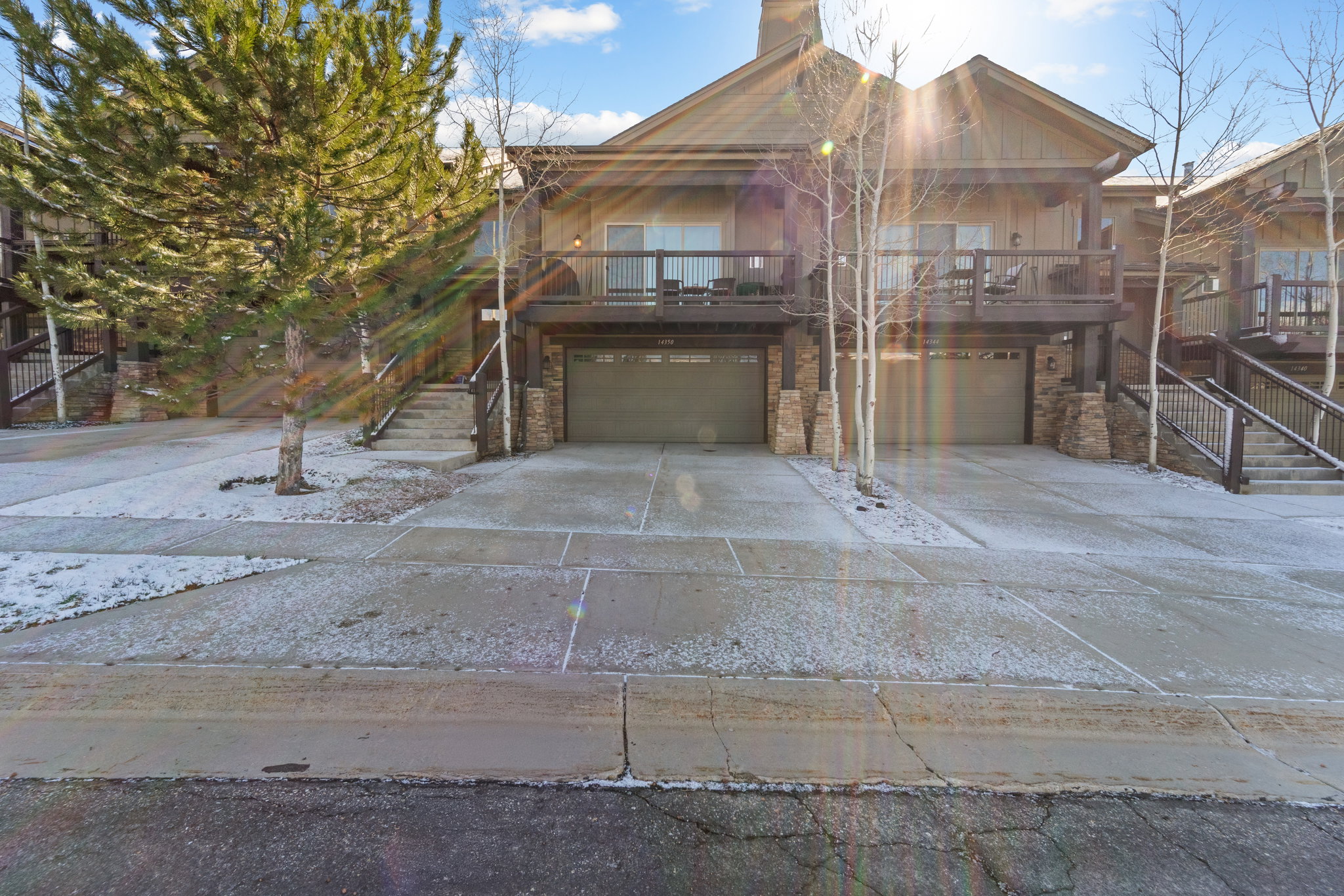 Rustic home with an attached garage, a deck, concrete driveway, and stone siding