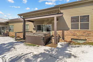 Rear view of house featuring stone siding, a hot tub, and a patio area
