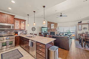 Kitchen featuring stainless steel appliances, light stone counters, a peninsula, a fireplace, and open floor plan