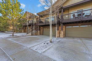 Rear view of house featuring driveway, an attached garage, board and batten siding, and a wooden deck