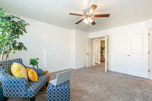 Living area featuring carpet and ceiling fan