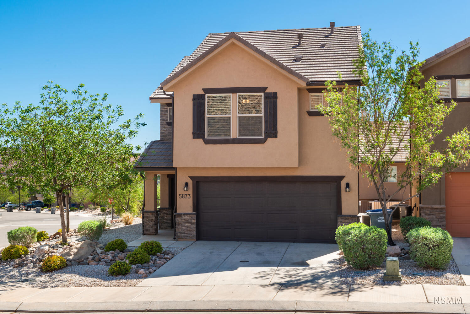 Traditional-style home with stone siding, a garage, stucco siding, and driveway