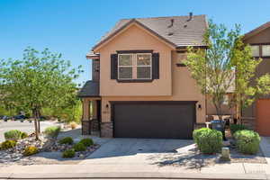 Traditional-style home with stone siding, a garage, stucco siding, and driveway