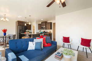 Living room with carpet floors, ceiling fan, and suspended lighting