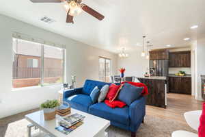 Living room featuring ceiling fan, light wood-style flooring, and hanging lights