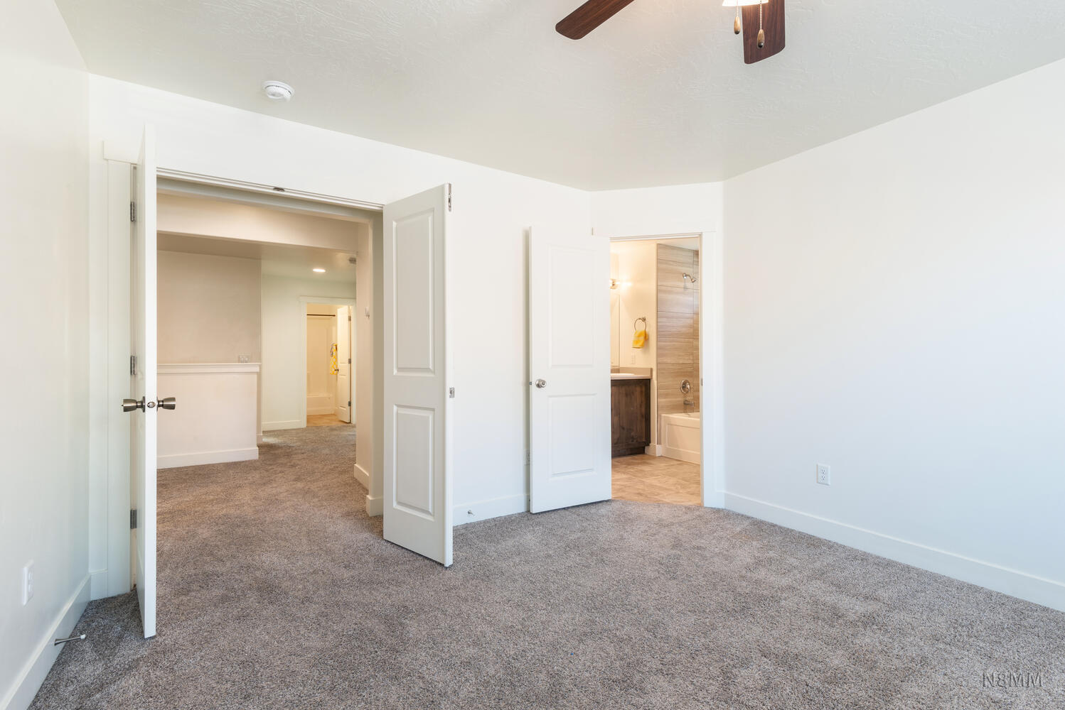 Unfurnished bedroom with light carpet, connected bathroom, and ceiling fan