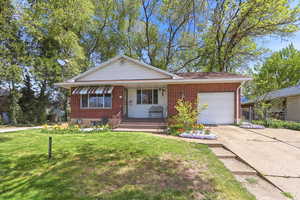 View of front of house featuring a garage, concrete driveway, a porch, and brick siding