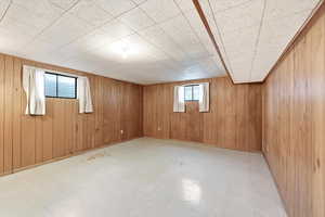 Below grade area featuring light flooring and wood walls