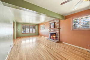 Unfurnished living room with light wood-type flooring, a fireplace, and ceiling fan