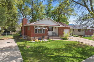 View of front of home featuring a chimney, brick siding, and driveway