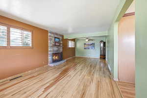 Unfurnished living room featuring a fireplace, light wood-style flooring, and ceiling fan