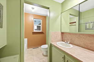 Bathroom featuring vanity, tasteful backsplash, and light tile patterned floors