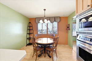 Dining space featuring light wood finished floors, a chandelier, and arched walkways