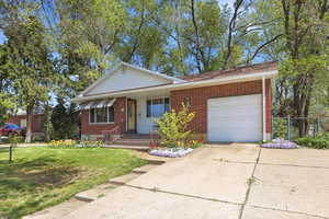 View of front of home with a garage, concrete driveway, covered porch, and brick siding