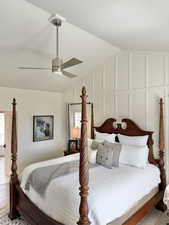 Bedroom with lofted ceiling, a decorative wall, ceiling fan, and wood finished floors