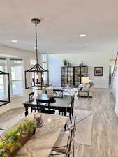 Dining area featuring light wood-type flooring, a textured ceiling, and suspended lighting