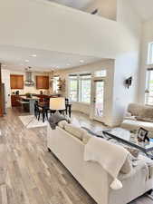 Living room with light wood-type flooring, recessed lighting, and a high ceiling