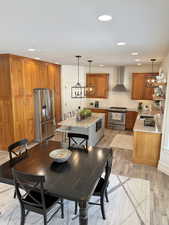 Dual tone kitchen with stainless steel appliances, light stone countertops, dual tone cabinets, light wood-style floors, and a center island