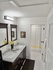 Full bath with double vanity, a textured ceiling, and a shower with shower curtain