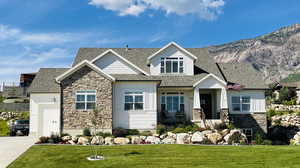 Craftsman inspired home with stone siding, board and batten siding, a shingled roof, and a front lawn