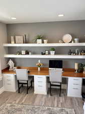 Home office with built in study area, light wood-type flooring, and recessed lighting