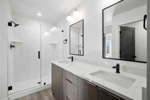 Photos of finished unit -Full bathroom featuring double vanity, a shower stall, and light wood-style floors