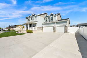 View of front of house featuring covered porch, a gate, driveway, and stone siding