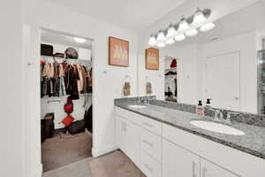 Full bathroom with a walk in closet, double vanity, and light carpet