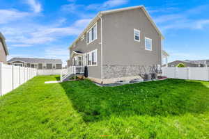 Rear view of property featuring stone siding, a fenced backyard, stucco siding, and a gate