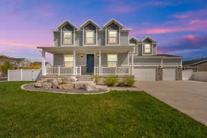 Traditional home featuring a porch, driveway, stone siding, a gate, and a garage
