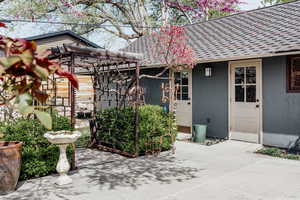 Entrance to property featuring stucco siding and roof with shingles