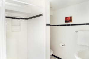 Bathroom featuring tile walls, a shower stall, wainscoting, and tile patterned floors