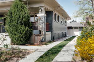 View of property exterior with brick siding, an outdoor structure, and a garage