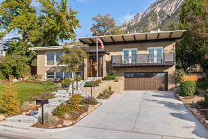 View of front facade with a balcony, driveway, an attached garage, and brick siding