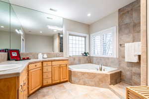 Full bathroom featuring double vanity, a bath, light tile patterned flooring, and a tile shower