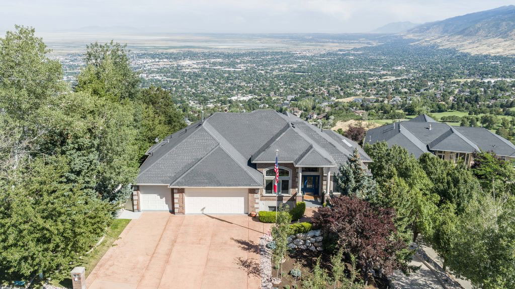 Elevated residence featuring a multi-car garage, mature landscaping, and an expansive mountain backdrop