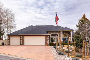 View of front of home with an attached garage, brick siding, driveway, and roof with shingles