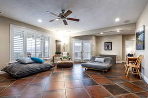 Living area with a textured ceiling, ceiling fan, and recessed lighting