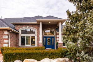 View of exterior entry featuring brick siding and a shingled roof
