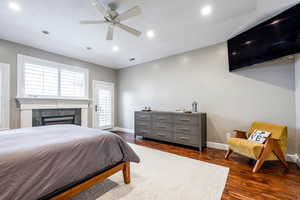 Bedroom featuring a tile fireplace, dark wood-type flooring, ceiling fan, and recessed lighting
